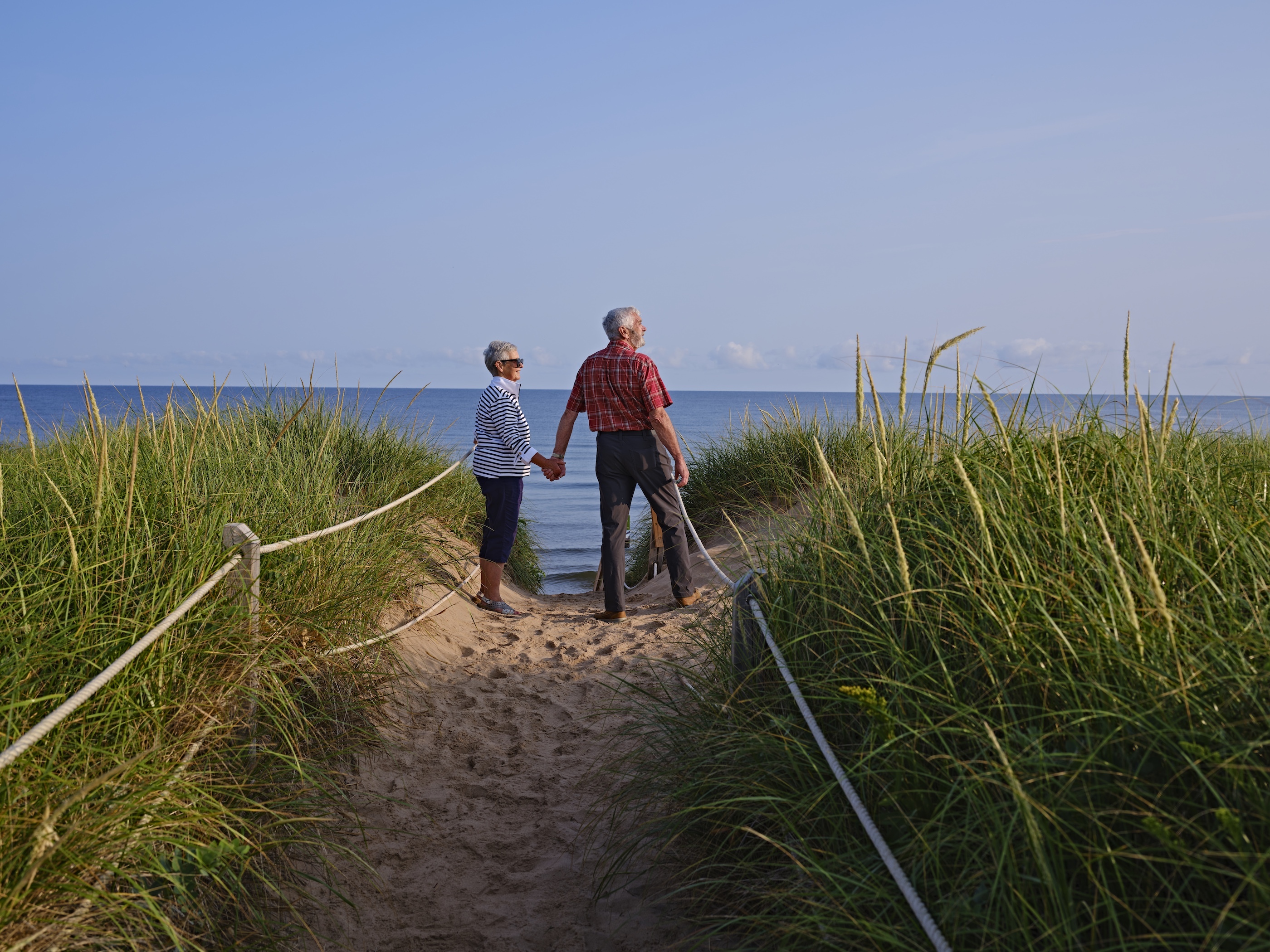 Older couple holding hands along the beach