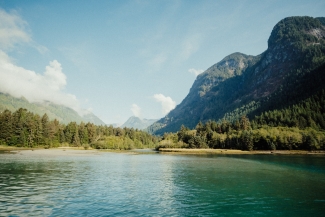 Lake nestled within mountains on a clear, sunny day with clouds