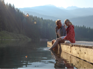 A couple sitting on a dock on a lake in Canada